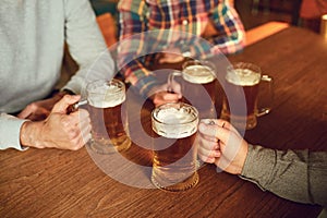 Glasses with beer in the hands of people in a bar.