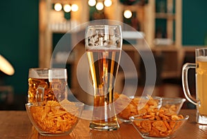 Glasses with beer and snacks on table in bar