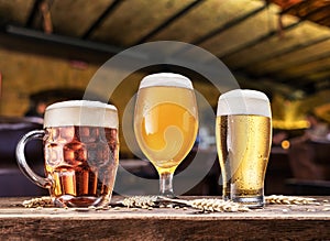 Glasses of beer on the wooden table. Blurred pub interior at the background. Assortment of beer