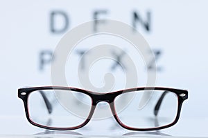 Glasses in black frame lying on background of eye test table closeup
