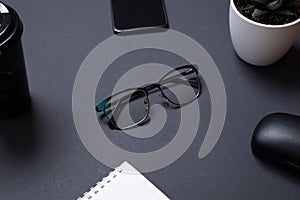 Glasses on black office desk surrounded by office supplies