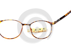 Glasses and a block of letters that read CLEAR, Clear vision on eyeglass lenses