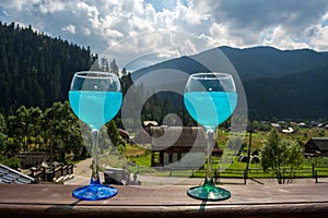 Glasses with blue champagne against the background of the mountains