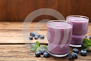 Glasses of blueberry smoothie with mint and fresh berries on wooden table. Space for text