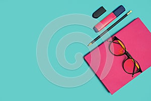 Glasses, book and stationery placed on blue background