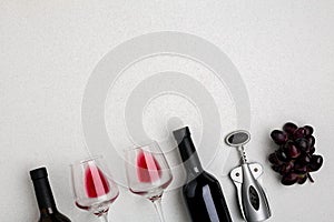 Glasses and bottles of red and white wine on white background from top view