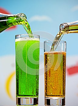 Glasses and bottles with tarragon and pear fizzy drinks isolated on summer background