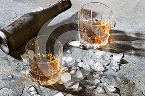 Glasses with brandy and melt ice cubes,bottle on bar counter