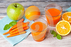 Glasses with carrot juice, apple, mint leaf and sliced orange