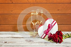 Glasses of champagne, heart shape gift box  and red roses. Concept of Valentine Day