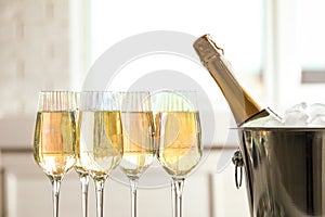 Glasses of champagne and ice bucket with bottle on background