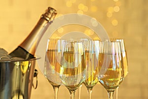 Glasses of champagne and ice bucket with bottle on blurred background