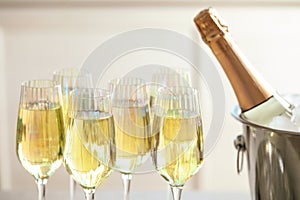 Glasses of champagne and ice bucket with bottle on blurred background