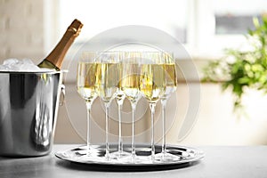 Glasses of champagne and ice bucket with bottle on table