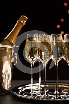 Glasses of champagne and ice bucket with bottle on table