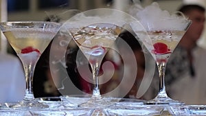 Glasses of champagne at a party, thick smoke from the glasses. Pyramid of sparkling drink.