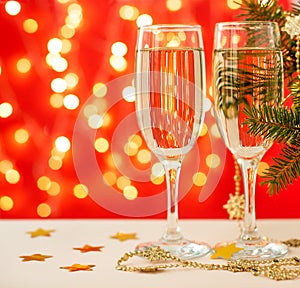 Glasses with champagne on a red background. holiday christmas. bokeh, lights, branches, garland, confetti. copy space
