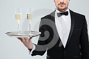 Glasses of champagne on tray holded by waiter in tuxedo