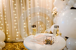 Glasses of champagne with wedding rings in a metal box and dry golden leaves. Luxury elegant wedding decor for the ceremony.