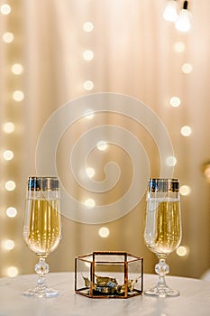 Glasses of champagne with wedding rings in a metal box and dry golden leaves. Luxury elegant wedding decor for the ceremony.