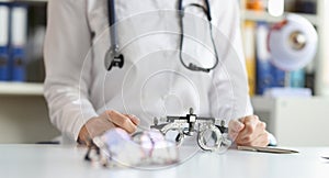 Glasses for checking vision lying on table near doctor ophthalmologist closeup