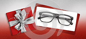 Glasses christmas gift card, red box with glittering silver ribbon bow, white ticket and black eyewear isolated on white