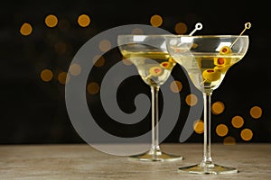 Glasses of Classic Dry Martini with olives on grey table against blurred background