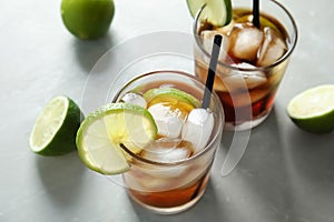 Glasses of cocktail with cola, ice and cut lime