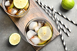 Glasses of cocktail with cola, ice and cut lime on grey background