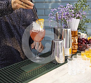 Glasses of cocktails on the bar. Bartender pours a glass of sparkling wine with red alcohol