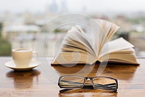 Glasses, coffee cup and open book