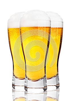 Glasses of cold beer with foam and froth on white