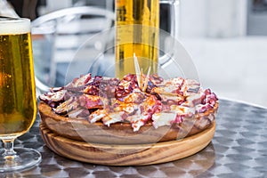 Glasses of cold Beer and Wooden plate of galician style cooked octopus with paprika and olive oil. Pulpo a la gallega