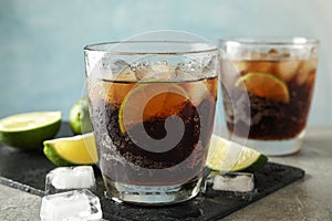 Glasses with cold cola and citrus on grey table