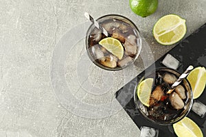 Glasses with cold cola and citrus on grey table