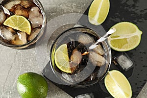 Glasses with cold cola and citrus on grey table