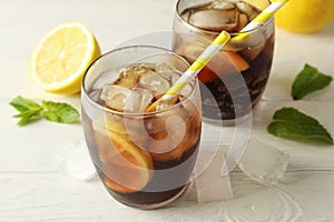 Glasses with cold cola and citrus on white cement background