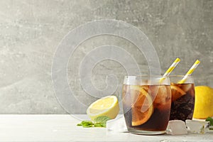 Glasses with cold cola and citrus on white cement background