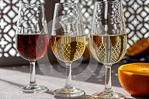 Glasses with cold dry fino and sweet cream sherry fortified wine and orange in sunlights, andalusian style interior on background