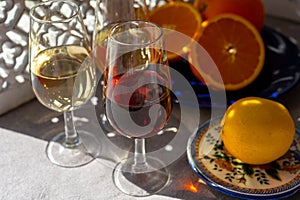 Glasses with cold dry fino and sweet cream sherry fortified wine and orange in sunlights, andalusian style interior on background