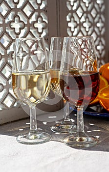 Glasses with cold dry fino and sweet cream sherry fortified wine and orange in sunlights, andalusian style interior on background