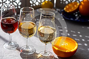 Glasses with cold dry fino and sweet cream sherry fortified wine and orange in sunlights, andalusian style interior on background