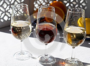 Glasses with cold dry fino and sweet cream sherry fortified wine and orange in sunlights, andalusian style interior on background