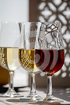 Glasses with cold dry fino and sweet cream sherry fortified wine in sunlights, andalusian style interior on background