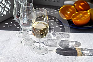 Glasses with cold fino sherry fortified wine and orange in sunlights, andalusian style interior on background