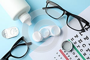 Glasses, contact lenses and eye test chart on blue background