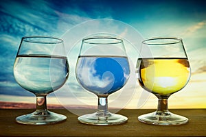 Glasses containing different skies. Brandy sniffer glassware with a different sunset in each one