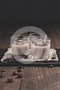 Glasses of Cream coffee liqueur with ice, and coffee  beans on rustic wooden background