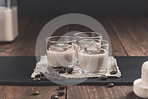 Glasses of Cream coffee liqueur with ice, and coffee  beans on rustic wooden background