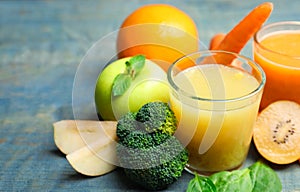 Glasses of delicious juices and fresh ingredients on blue wooden table, closeup. Space for text